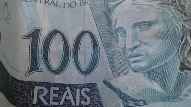 Calculadora ao lado de notas de dinheiro sobre uma mesa