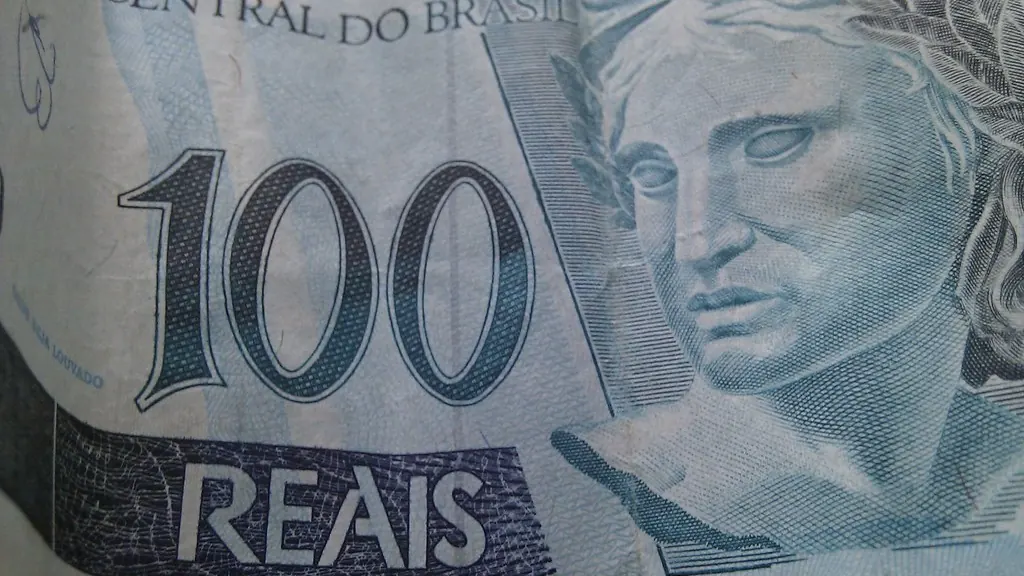 Calculadora ao lado de notas de dinheiro sobre uma mesa