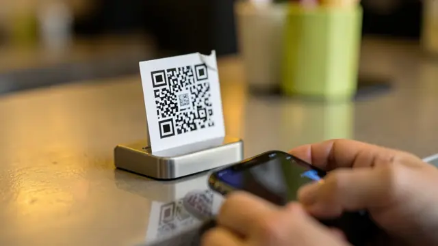 Adesivo de QR Code colado por cima de outro no balcão de um restaurante