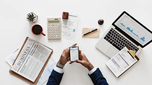 Mãos segurando um celular com o app do banco aberto, à noite